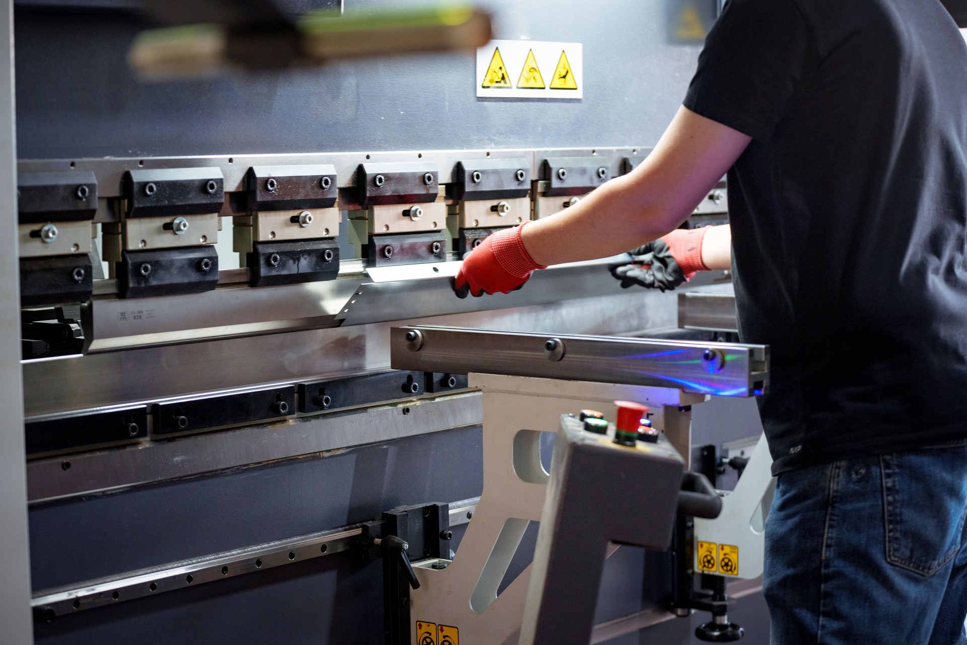 Worker bends metal on the machine, Employee operates bending machine in a metalworking company - bending of sheet metal for further processing