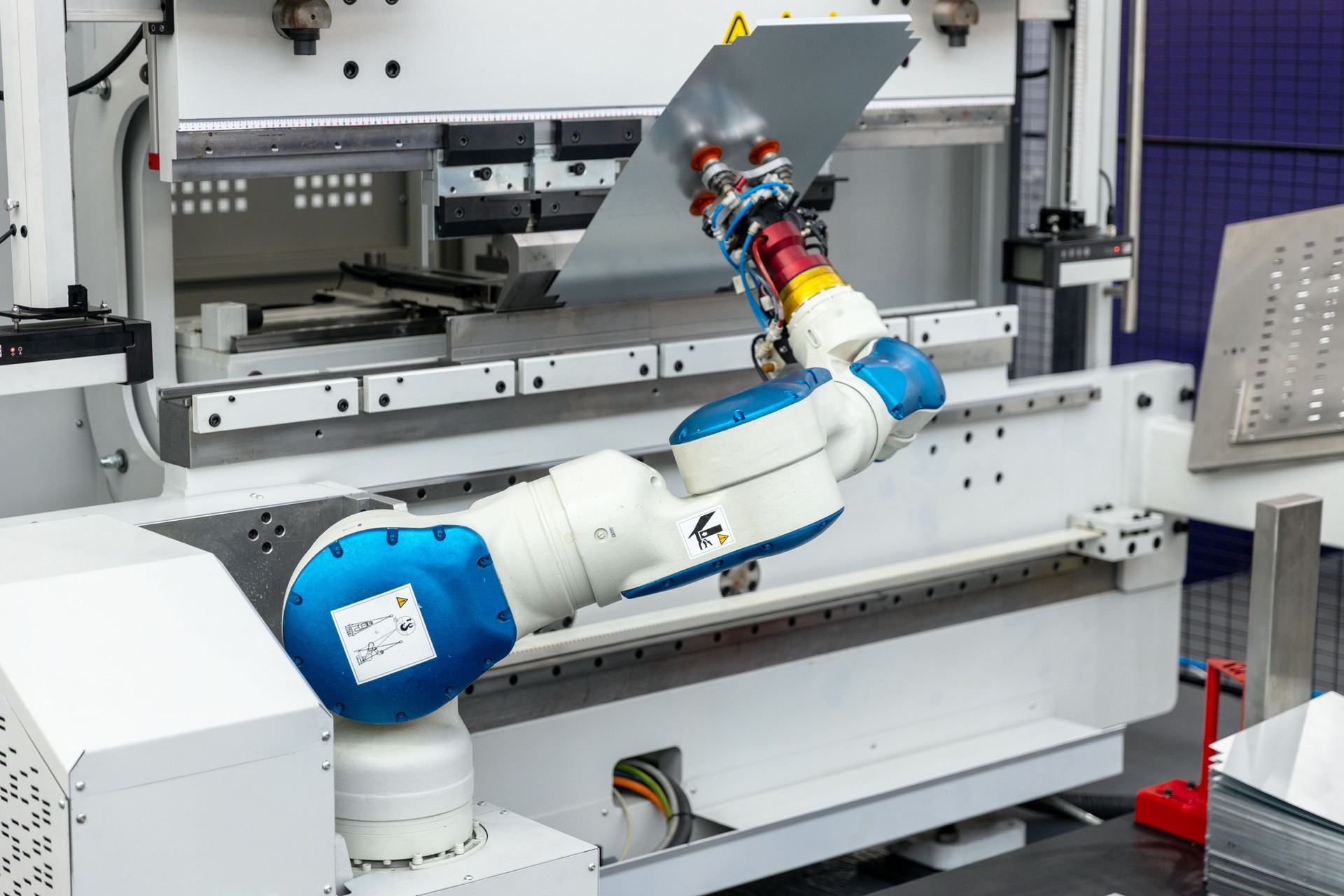 Industrial robotic arm handling sheet metal with high precision in a smart factory setting with advanced automated machinery and safety systems