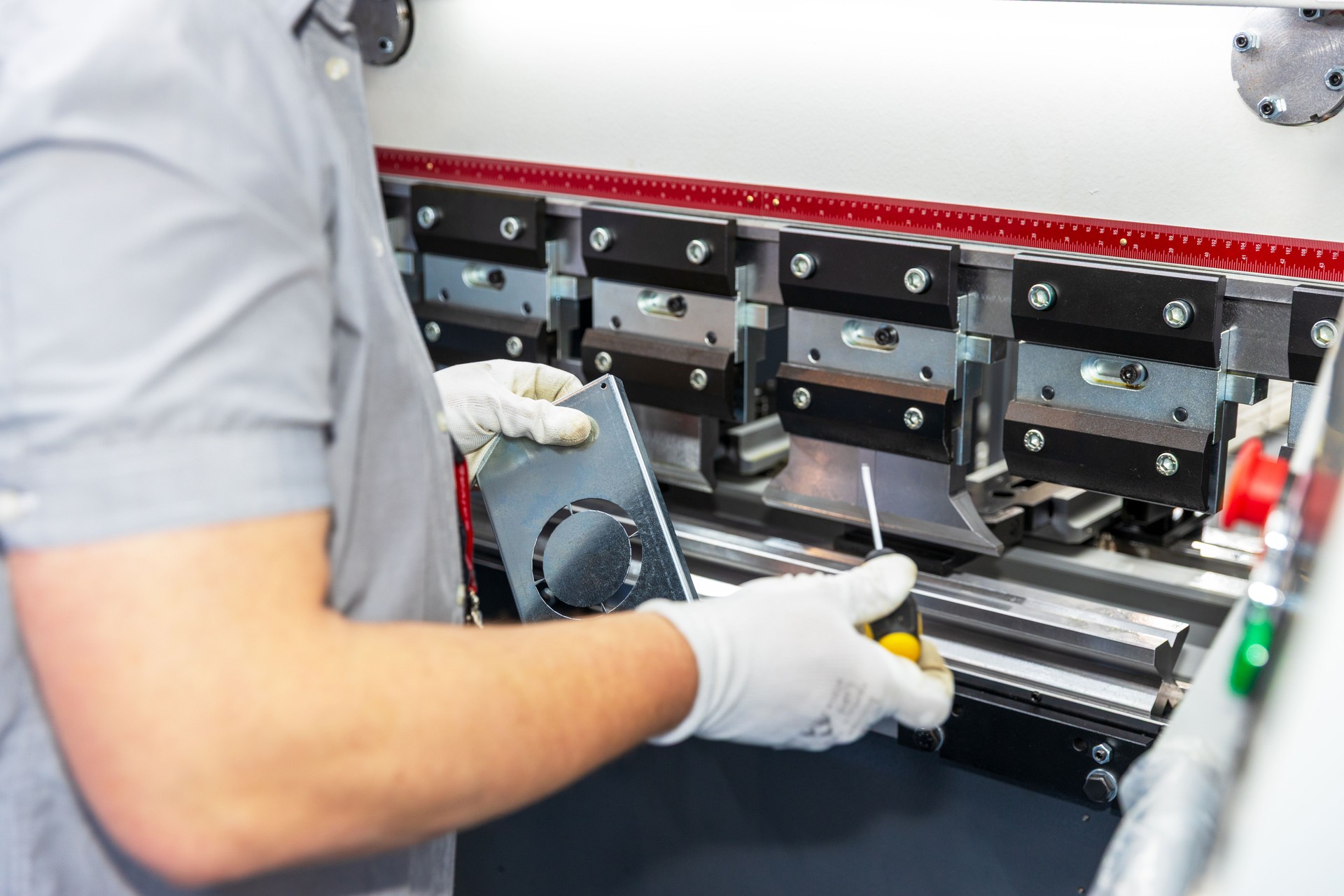 Technician operating CNC press brake machine in factory
